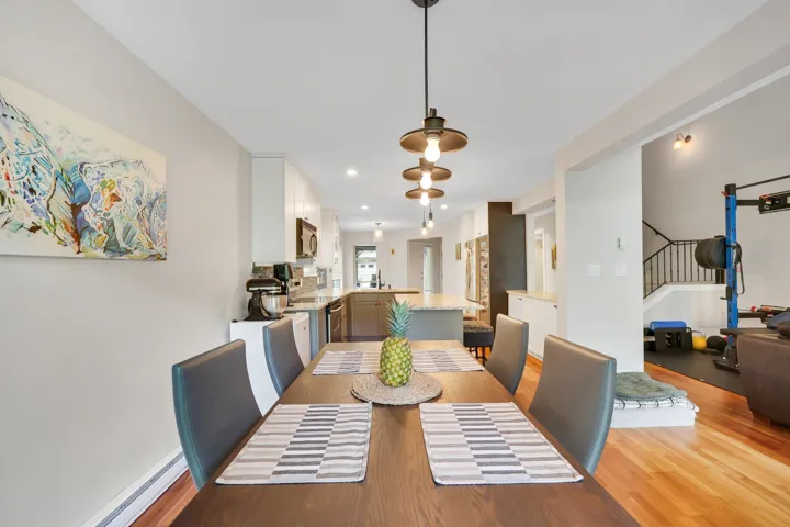 Open-concept dining area featuring a dark wood-finish dining table and coordinated pendant lighting