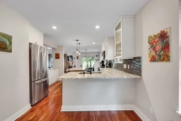 Kitchen with wood-finish flooring, white cabinetry, a stainless steel refrigerator, and light-toned countertops