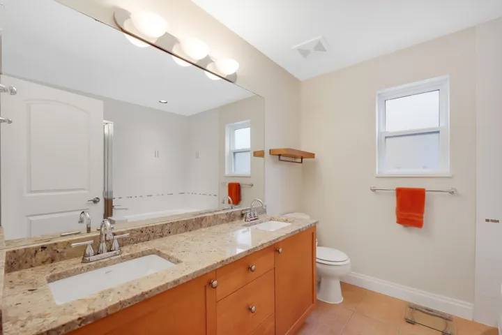 Double vanity with granite-style countertop, dual undermount sinks, and wood-finish cabinetry