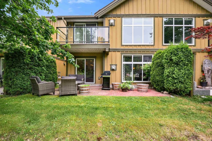 Rear exterior featuring a brick patio and a grassy area
