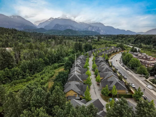 Aerial perspective of a residential community situated against a mountain range and surrounded by extensive natural landscaping