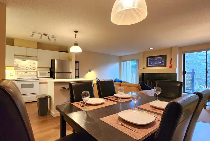 Dining space with light wood-style flooring, a textured ceiling, and a tiled fireplace