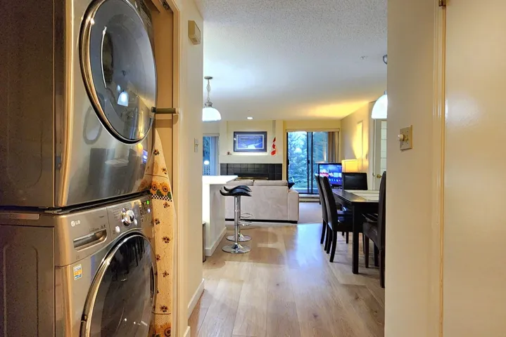 Washroom with light wood-style floors, stacked washing machine and dryer, and a textured ceiling