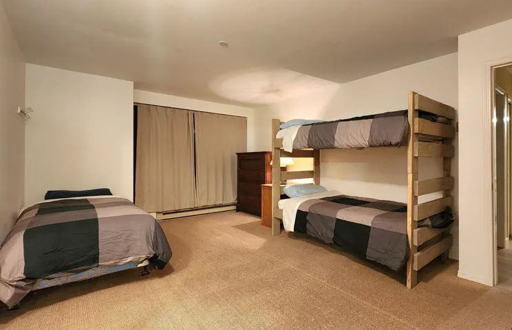 Bedroom featuring light carpet and baseboard heating