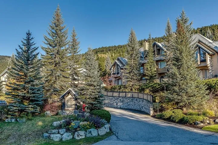 View of front facade with a wooded view and driveway