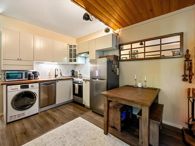 Kitchen featuring washer / clothes dryer, appliances with stainless steel finishes, decorative backsplash, dark wood-type flooring, and glass insert cabinets