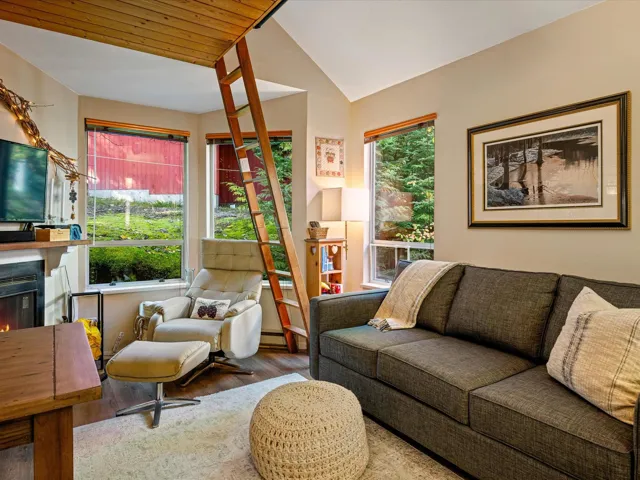 Living area featuring lofted ceiling, wood finished floors, and a lit fireplace