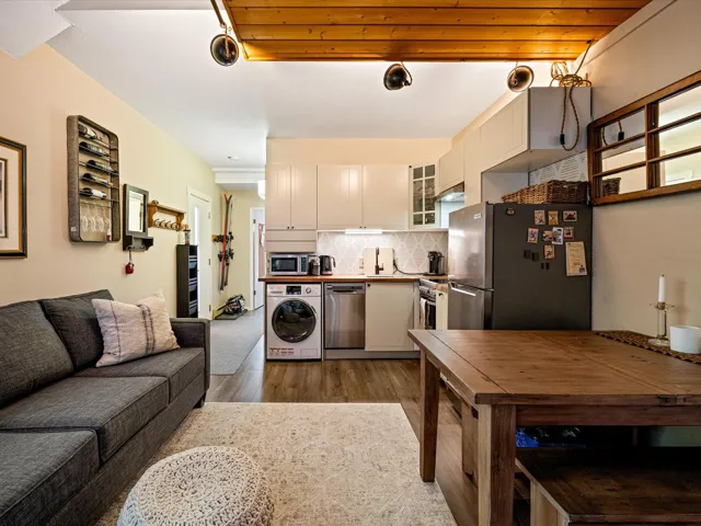 Kitchen featuring decorative backsplash, washer / dryer, stainless steel appliances, glass insert cabinets, and wood finished floors