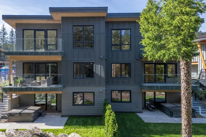 Back of house featuring a hot tub, a balcony, a patio area, and board and batten siding
