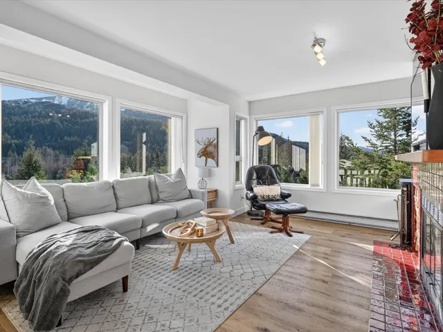 Living room with a brick fireplace, light wood-style flooring, and a baseboard heating unit