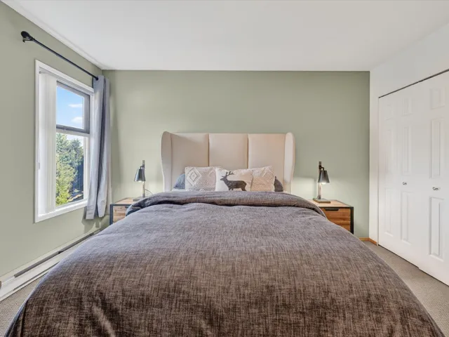 Carpeted bedroom with a closet and a baseboard heating unit