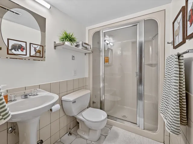 Full bath featuring a stall shower, tile walls, a wainscoted wall, and tile patterned flooring