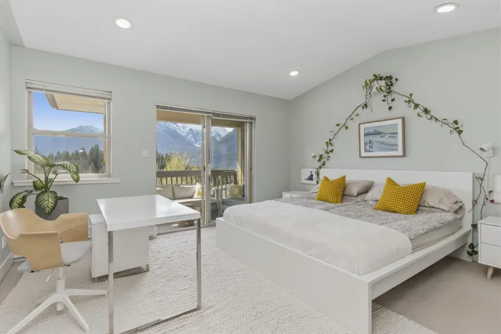 Spacious living area featuring large windows, a fireplace with a light-toned mantel, built-in shelving, and wood-finish flooring
