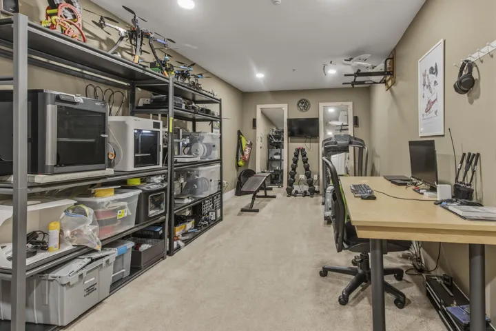 Garage space featuring a concrete floor, built-in shelving, white cabinetry, and overhead lighting fixtures