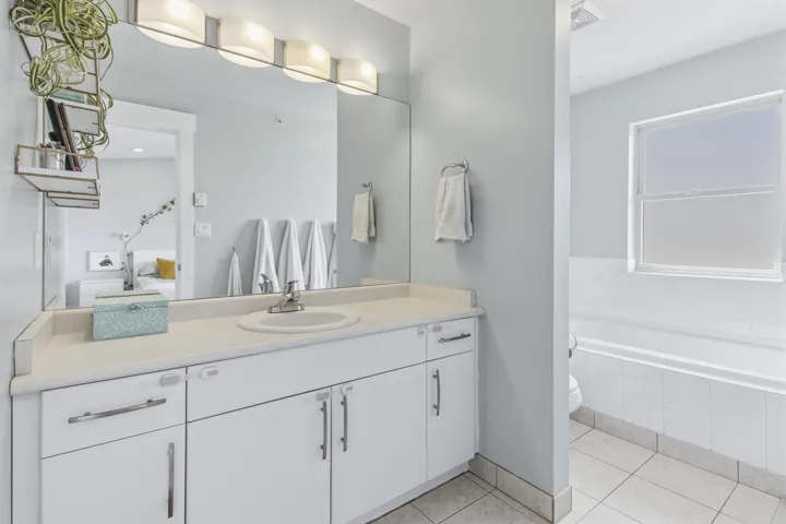 Vaulted ceiling, recessed lighting, expansive windows, sliding glass door access to an outdoor balcony, and a built-in wall sconce