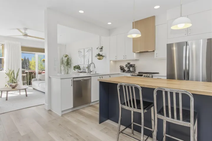 Laundry area featuring a built-in utility sink, white cabinetry with chrome hardware, wood-finish countertop, and light-toned flooring
