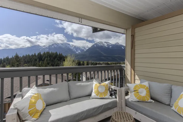 Expansive window framing mountain scenery, wood-finish ceiling fan, built-in fireplace, and sliding glass door leading to a balcony