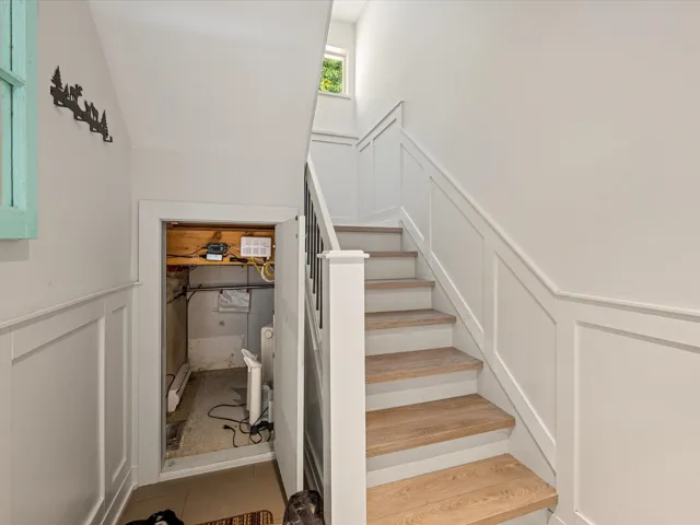 Staircase featuring a decorative wall, wainscoting, and tile patterned floors