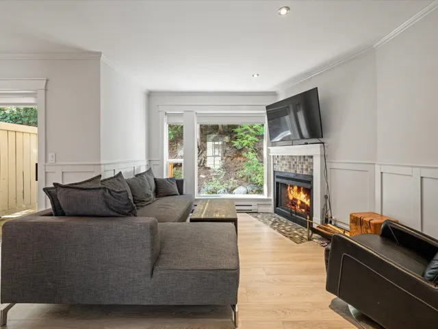 Living room with a decorative wall, a wainscoted wall, crown molding, light wood finished floors, and a tile fireplace