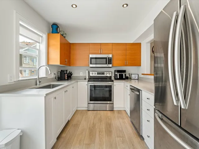 Kitchen with stainless steel appliances, recessed lighting, light wood-type flooring, light stone countertops, and white cabinetry