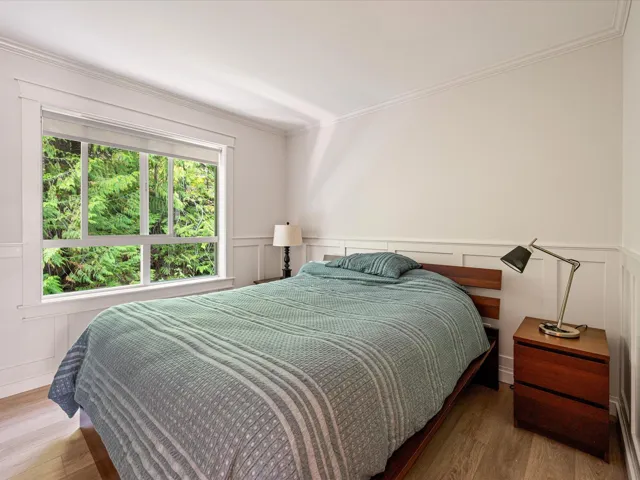 Bedroom featuring crown molding, wood finished floors, a decorative wall, and wainscoting