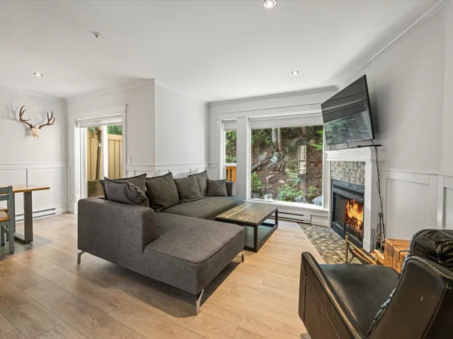 Living area featuring a decorative wall, wainscoting, ornamental molding, light wood-style flooring, and a tile fireplace