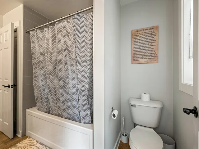 Full bath featuring shower / tub combo with curtain and wood finished floors