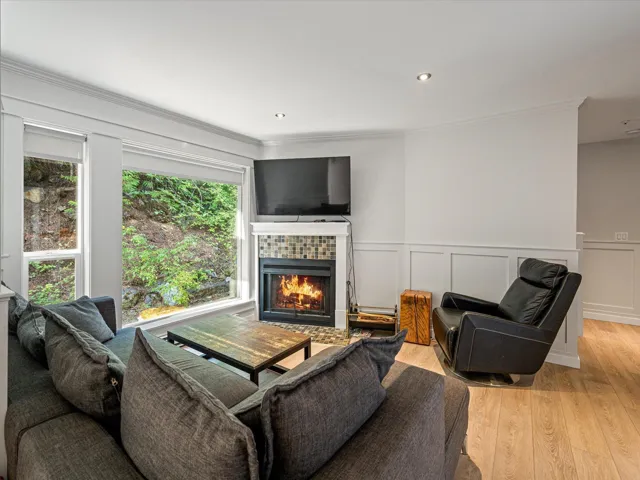 Living room featuring a decorative wall, wood finished floors, ornamental molding, a tile fireplace, and recessed lighting
