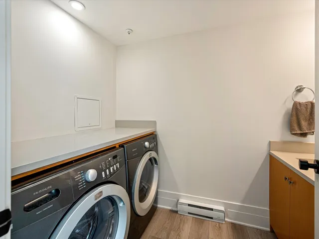 Washroom featuring a baseboard radiator, light wood-type flooring, washer and clothes dryer, and recessed lighting