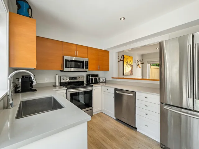 Kitchen featuring stainless steel appliances, light wood finished floors, recessed lighting, brown cabinetry, and light stone countertops