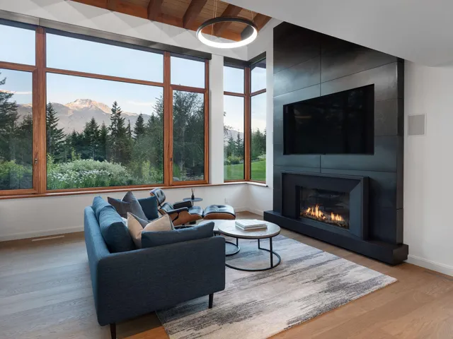 Living room with a large fireplace, light wood-type flooring, and a wood ceiling with exposed beams
