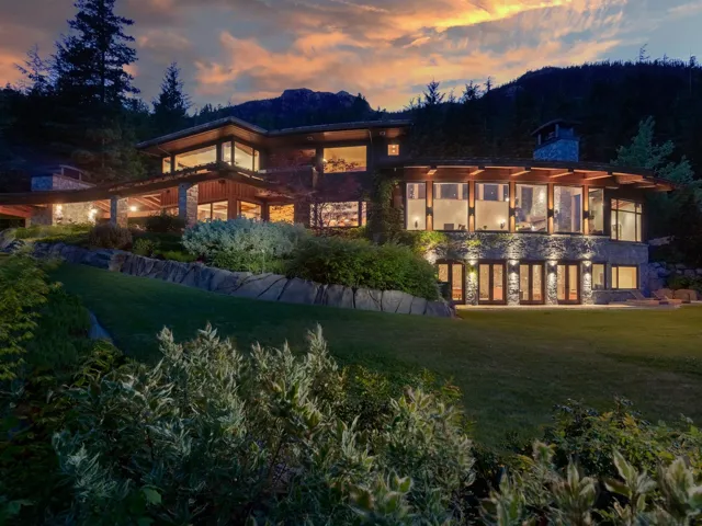 Back of property at dusk with a yard, a balcony, a patio area, and a chimney