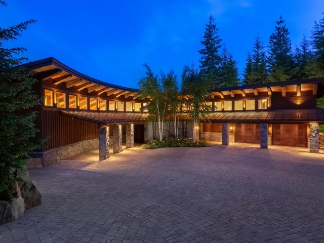 View of front facade with stone siding, decorative driveway, and board and batten siding