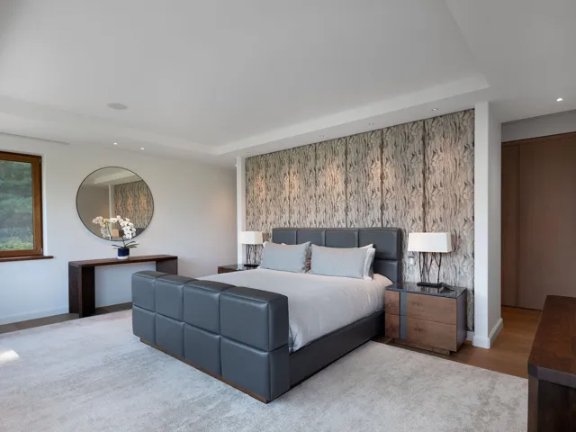 Bedroom with recessed lighting, a raised ceiling, an accent wall, and wood finished floors