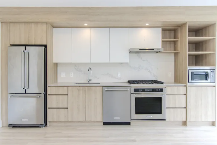 Kitchen with light brown cabinetry, stainless steel appliances, open shelves, modern cabinets, and decorative backsplash