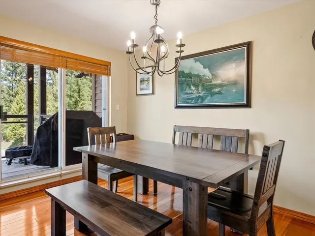 Dining space featuring wood-finish flooring, a contemporary chandelier, and a sliding glass door leading to an outdoor balcony