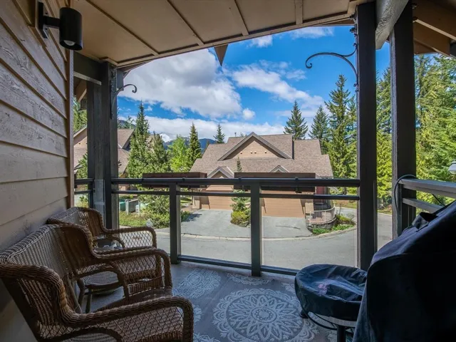 Balcony featuring wood siding, a glass and metal railing, and a decorative outdoor light fixture
