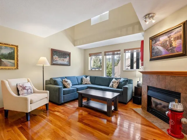 Living area featuring wood-finish flooring, a tile-surround fireplace with a wooden mantel, and multiple windows
