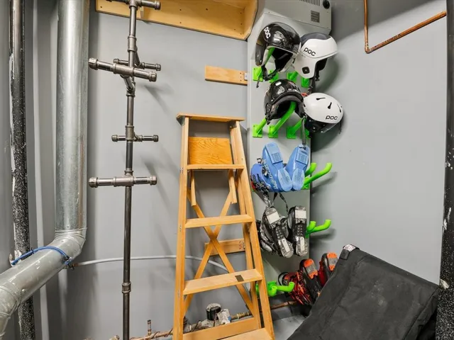 Utility room featuring a wall-mounted drying rack system and exposed piping