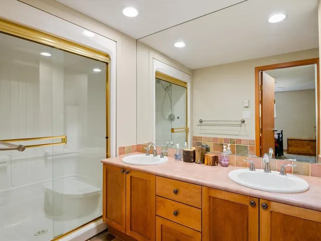 Double vanity with undermount sinks, wood cabinetry, and a tile backsplash