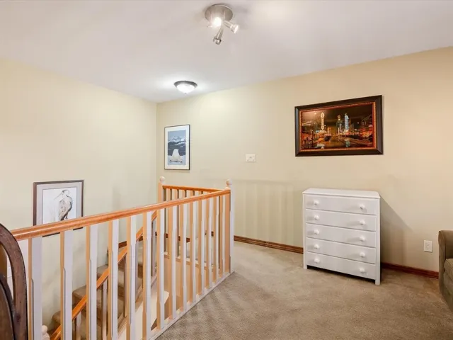 Carpeted landing featuring a two-tone wood railing system and ceiling-mounted light fixtures