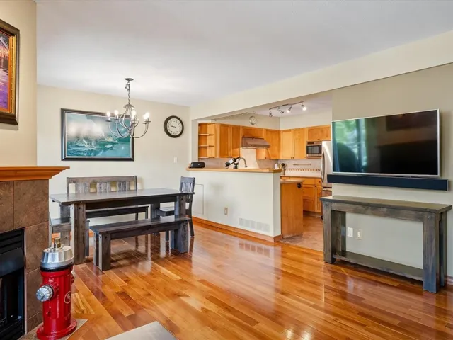 Warm wood-finish flooring extends through the main living areas, complemented by a tiled fireplace surround