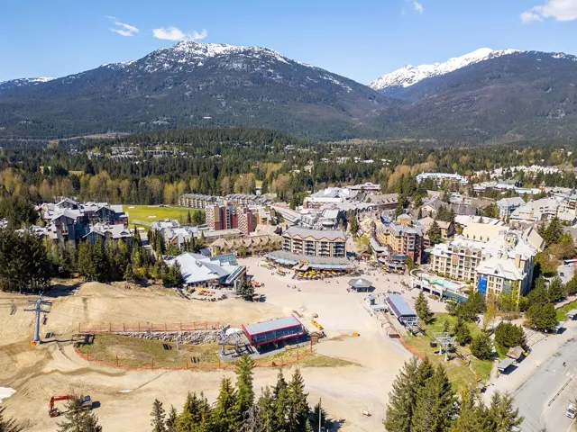 Expansive mountain resort village featuring multiple multi-story buildings, ski lifts, and a central plaza