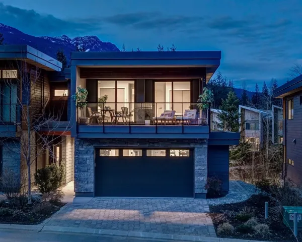 Modern home with a balcony, a mountain view, stone siding, decorative driveway, and a garage