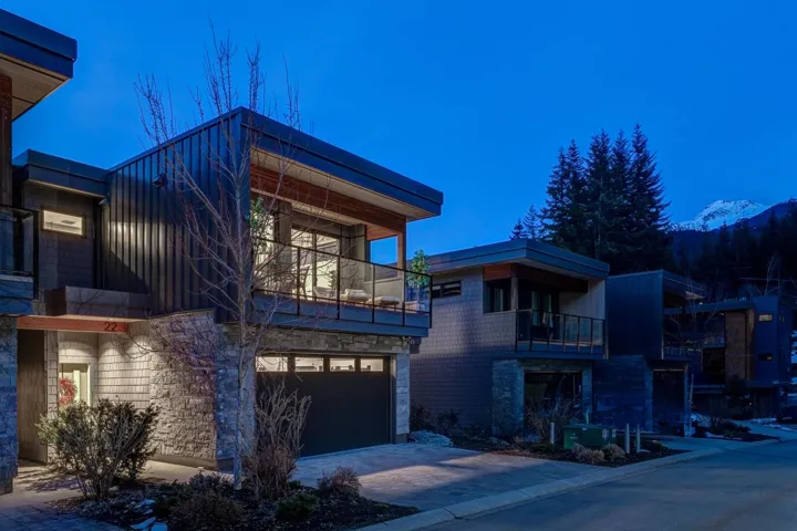 View of side of home with a balcony, driveway, board and batten siding, and stone siding