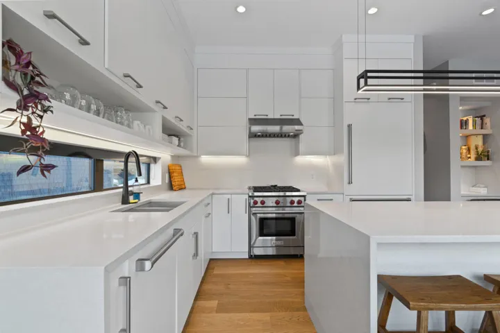 Kitchen with open shelves, a kitchen breakfast bar, light stone counters, and recessed lighting
