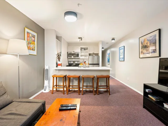 Living area with dark colored carpet and baseboards