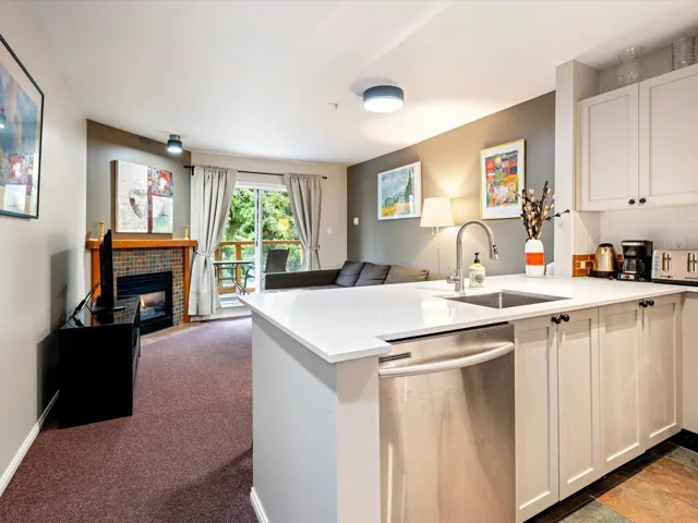 Kitchen featuring open floor plan, dishwasher, a peninsula, a tile fireplace, and white cabinets