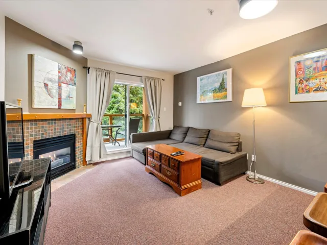 Carpeted living area with a tiled fireplace and baseboards