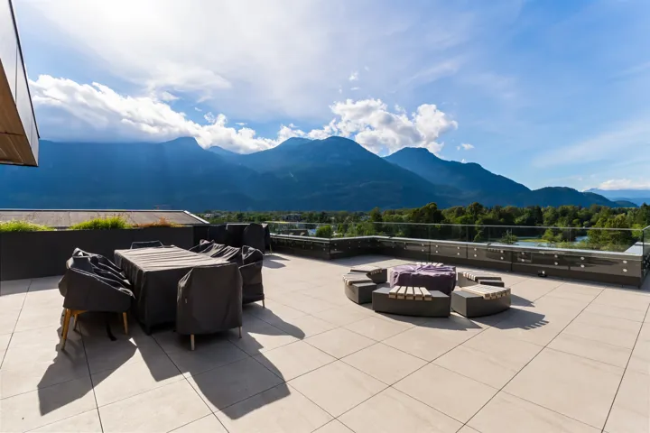Expansive rooftop deck featuring light-toned large format tile, a glass railing system, and built-in perimeter planters